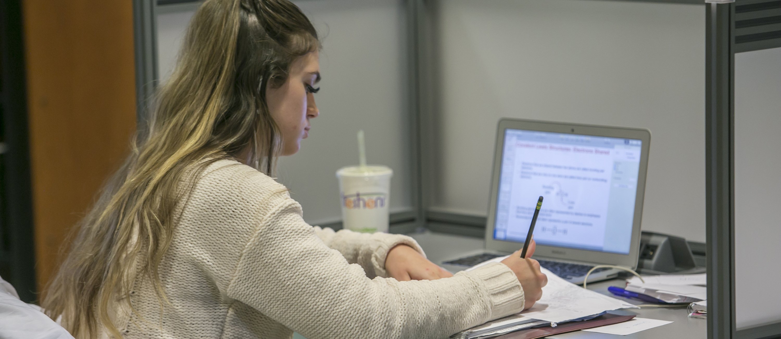 student writing near a laptop